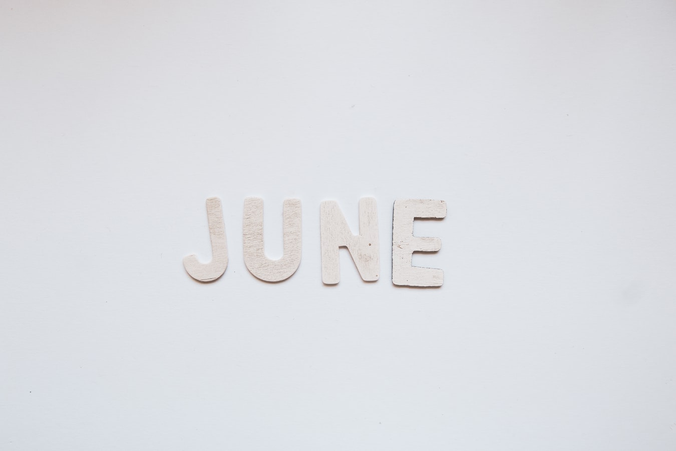 'June' written using paper cut letters, over a white background