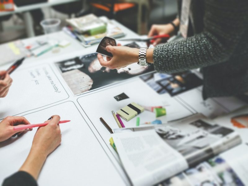 group of people working together around a table which is full of papers and post its.