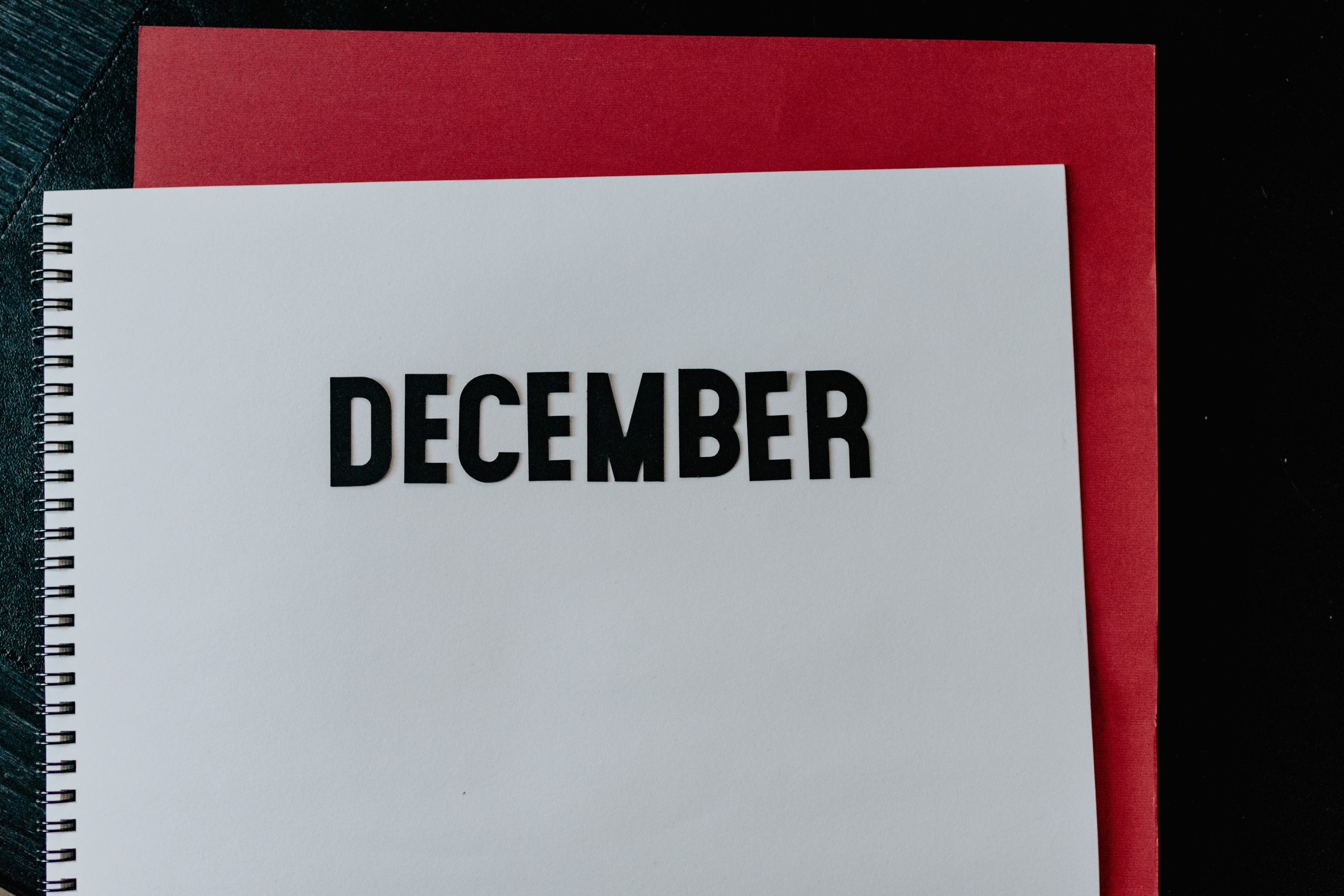 Notebook open in a blank page, the word December is written on it