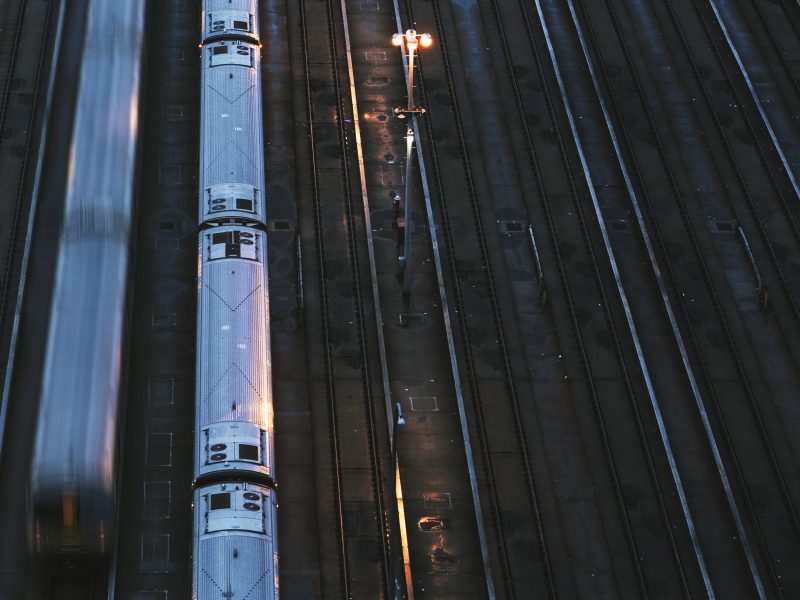 train tracks photographed from above. there are two free tracks, a train parked over one, and a train passing over another one