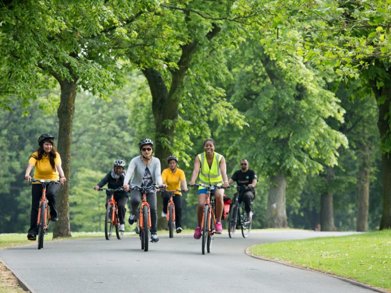 a group of people is cycling on a path in a park