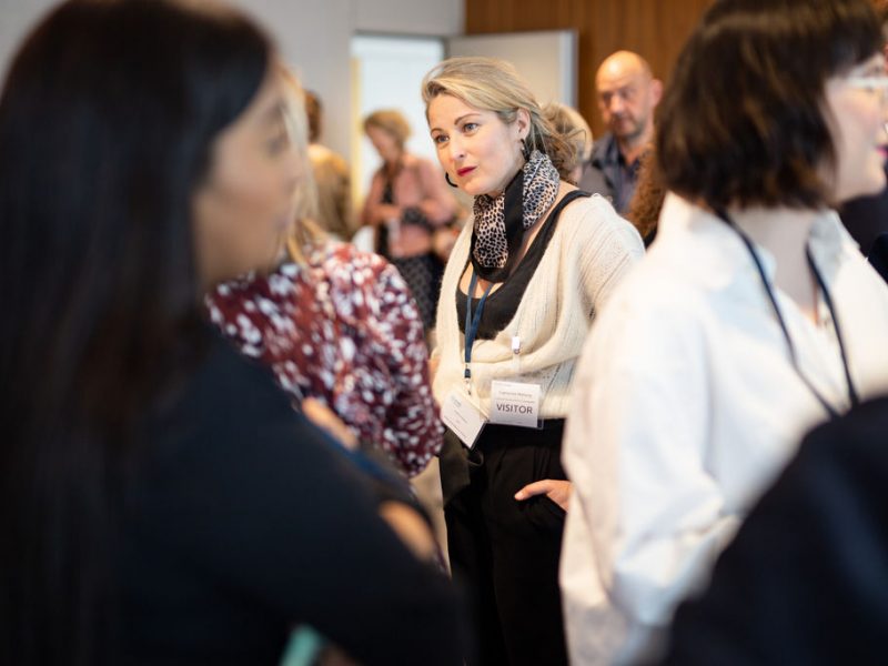 a room full of people socialising, everyone is standing up