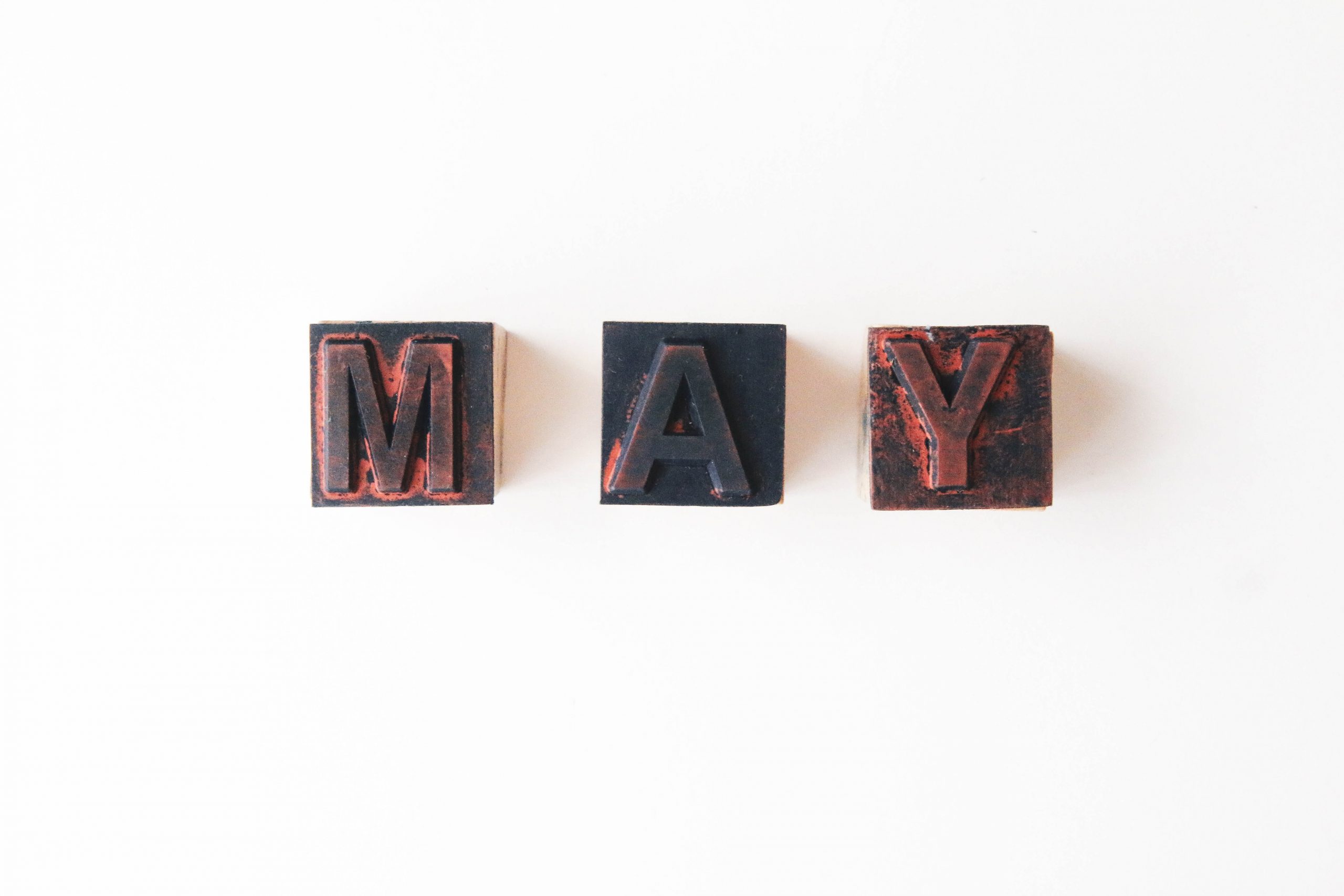 the letters M, A and Y over wooden stamps, forming the word MAY