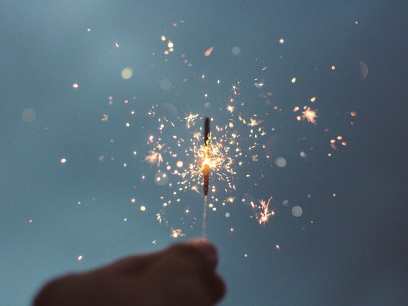 Hand holding a sparkler against a cloudy background