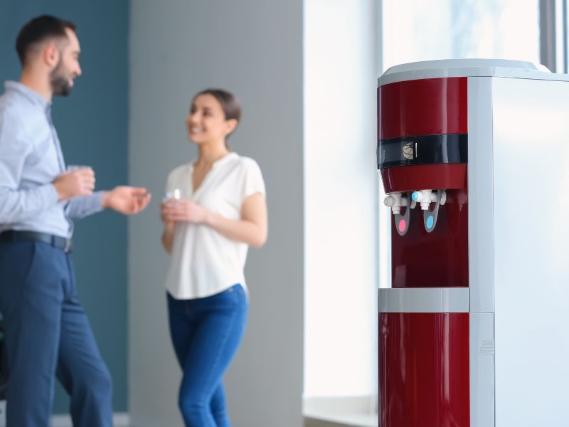 two people standing near a watercooler, they are having a chat