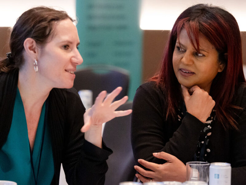 two women sitting side by side, one is speaking and the other is paying attention