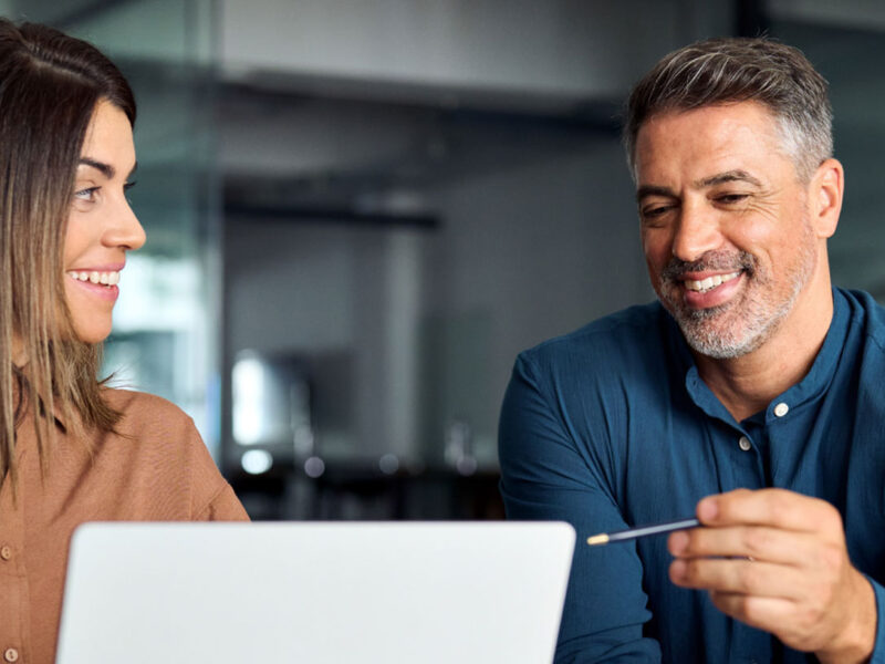 two people looking at a laptop screen and chatting about what they see