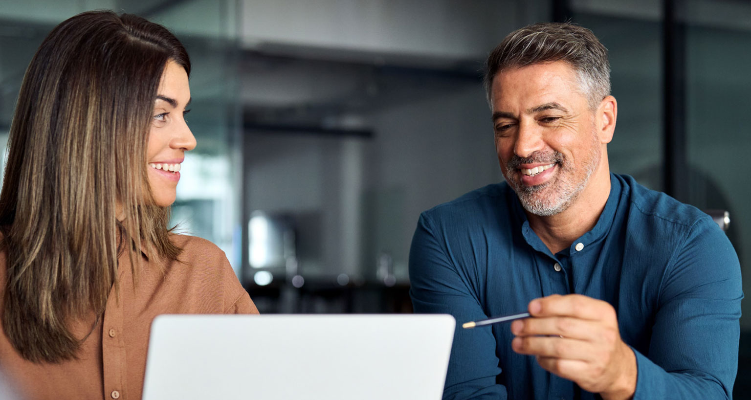 two people looking at a laptop screen and chatting about what they see