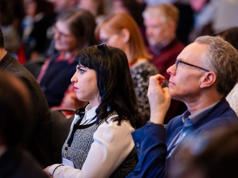 people attending a conference, sitting down watching someone speak