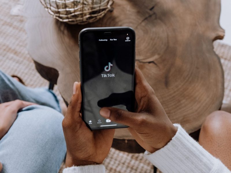 photo of a person holding a phone, opening the Tiktok app