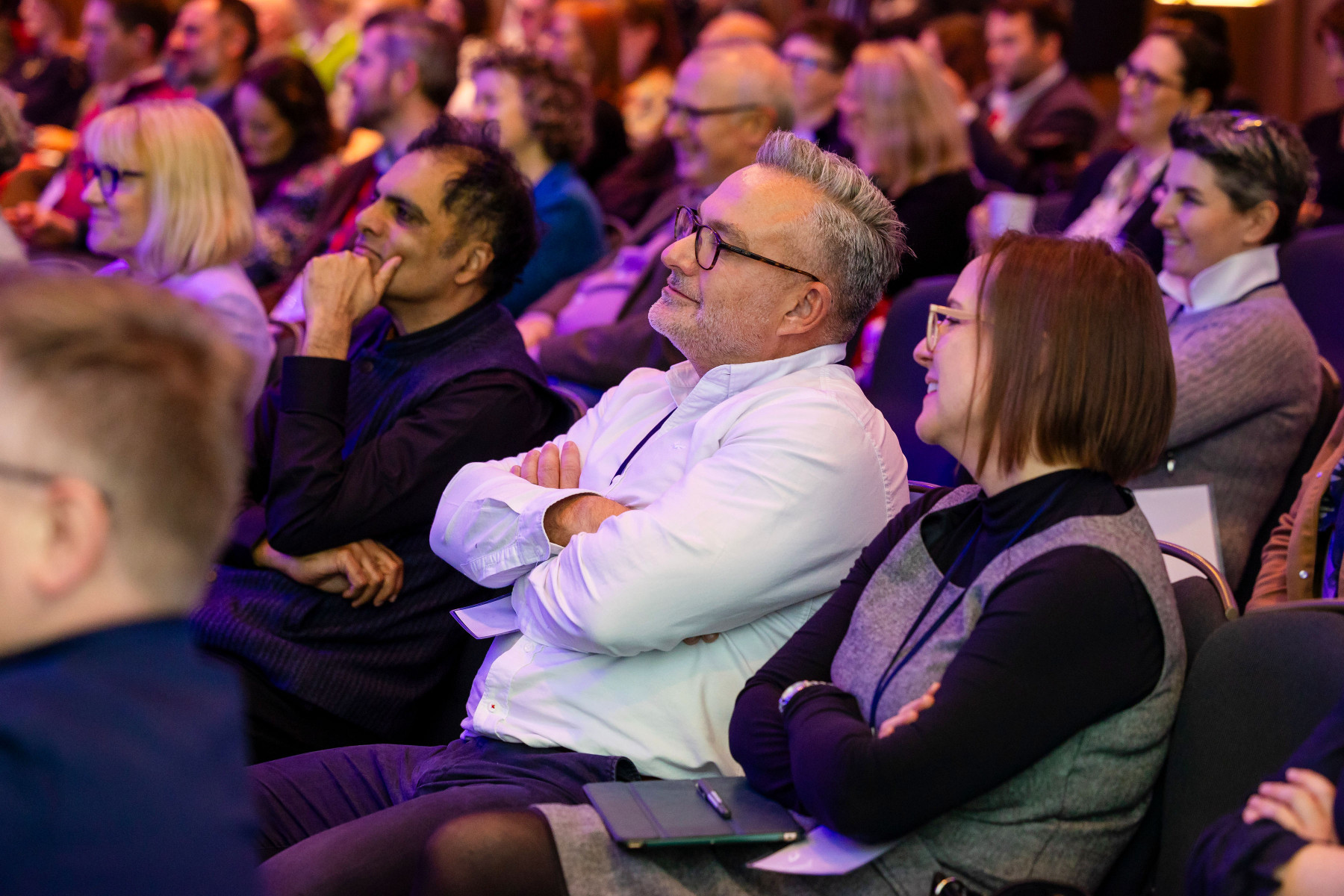 conference audience. people sitting within an auditorium, all looking towards the stage